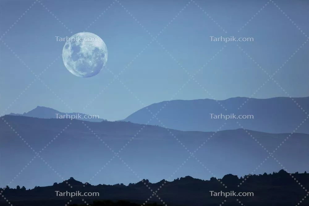 شبح کوهها در سیلوئت و ماه در آسمان شب