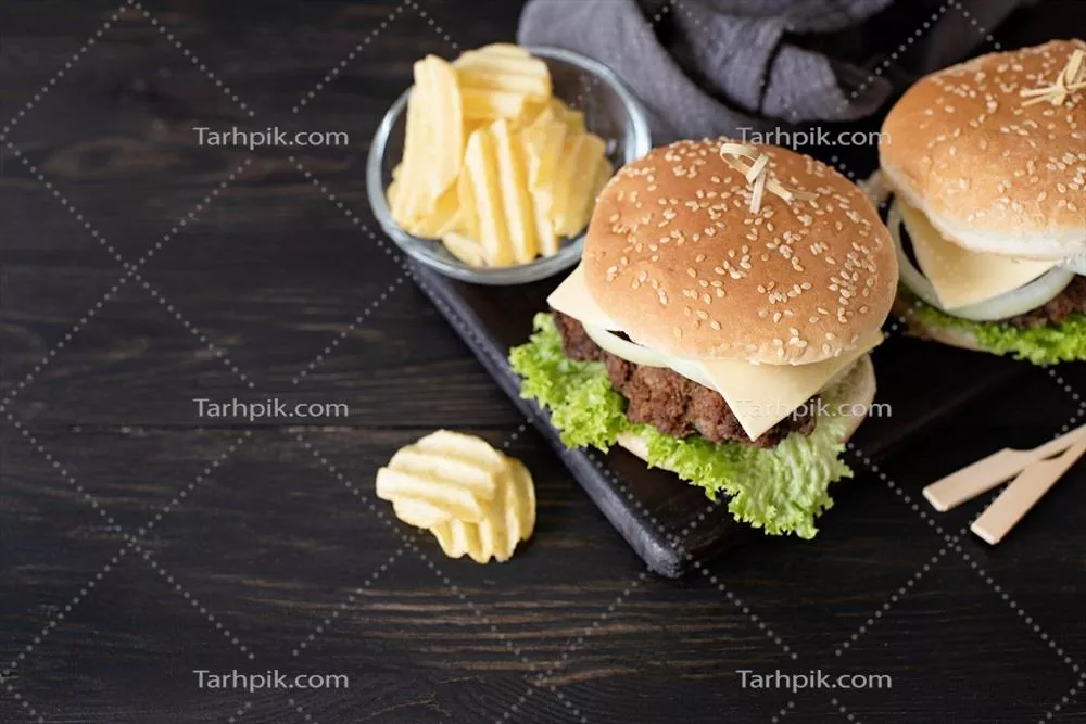 مجموعه ای از برگرهای خانگی خوشمزه با گوشت، پیاز، پنیر و کاهو بر روی زمینه چوبی تیره