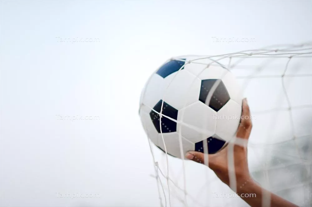 تصویر بریده شده از بازیکنان ورزشی که توپ را در زمین فوتبال می‌گیرند