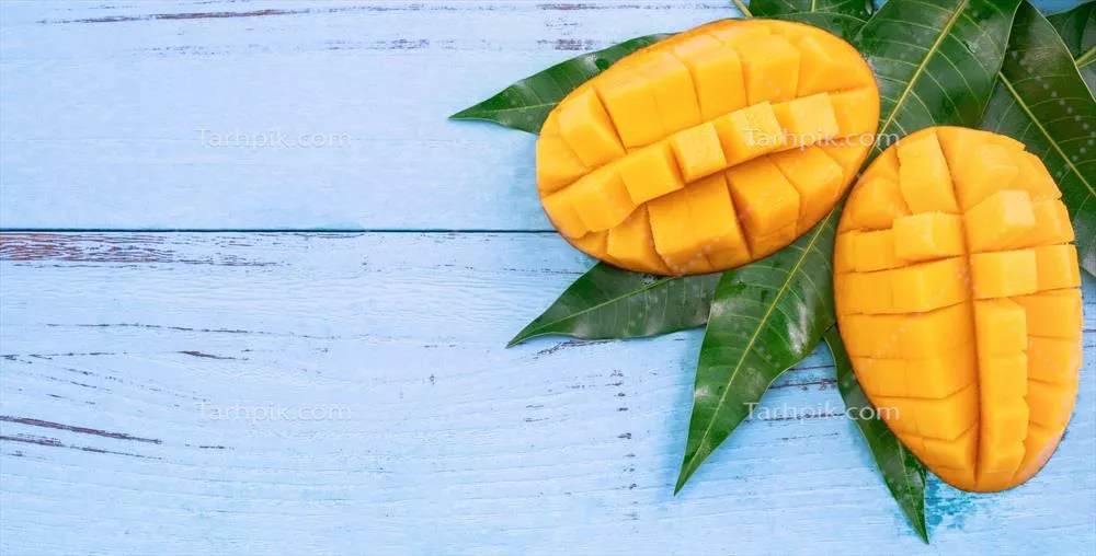 مغز تازه و خرد شده انبه با برگ های سبز بر روی چوب آبی روشن - تصویر نمای بالا