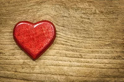 شکلات قلبی قرمز بر روی پسزمینه چوبی قدیمی و زیبا