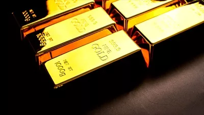تعدادی شمش طلای درخشان بر روی میز، نماد ثروت و قدرت