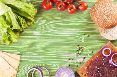 مواد اولیه برای تهیه همبرگر بر روی پسزمینه چوبی سبز