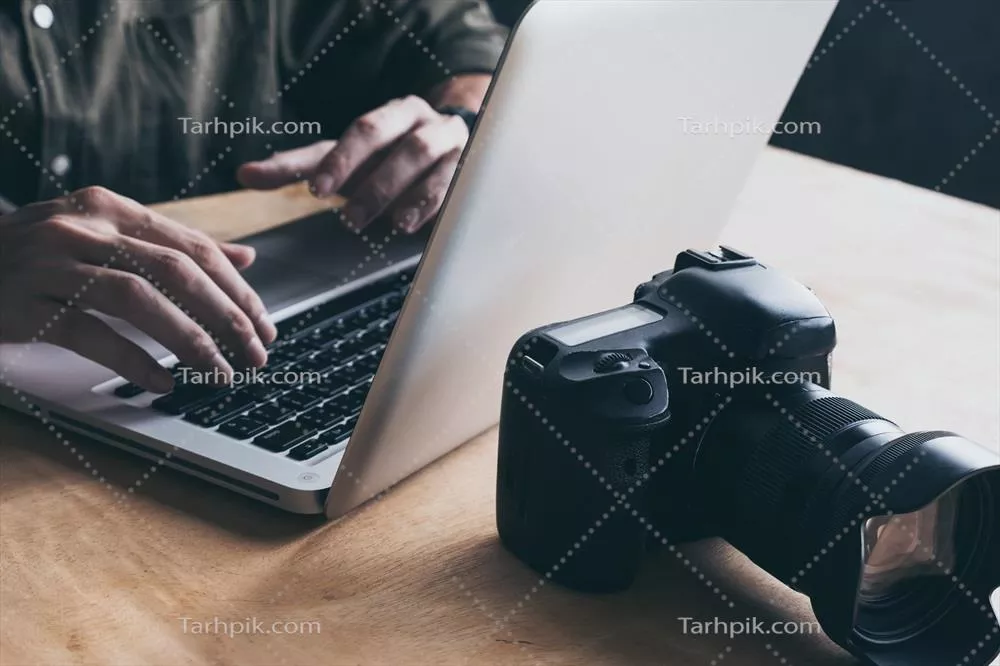 عکاس در حال ویرایش تصاویر خود با لپتاپ در نما نزدیک