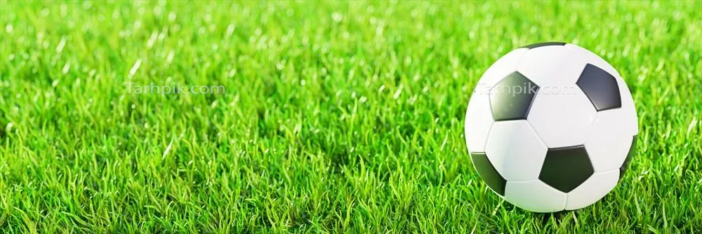 تصویری واقعی از توپ فوتبال با طراحی ساده روی چمن سبز زیر نور خورشید
