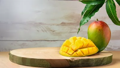 تصویری دلنشین از درخت انبه با میوه‌های آویزان بر روی میز چوبی روستایی