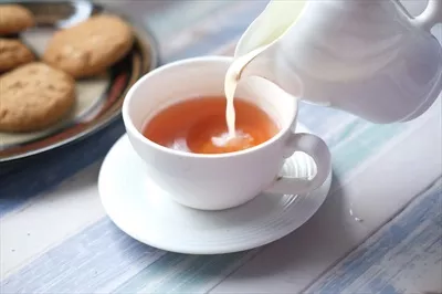 تصویری نزدیک از ریختن شیر در فنجان چای