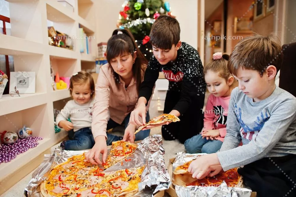 خانواده شاد با چهار کودک در حال خوردن پیتزا در خانه