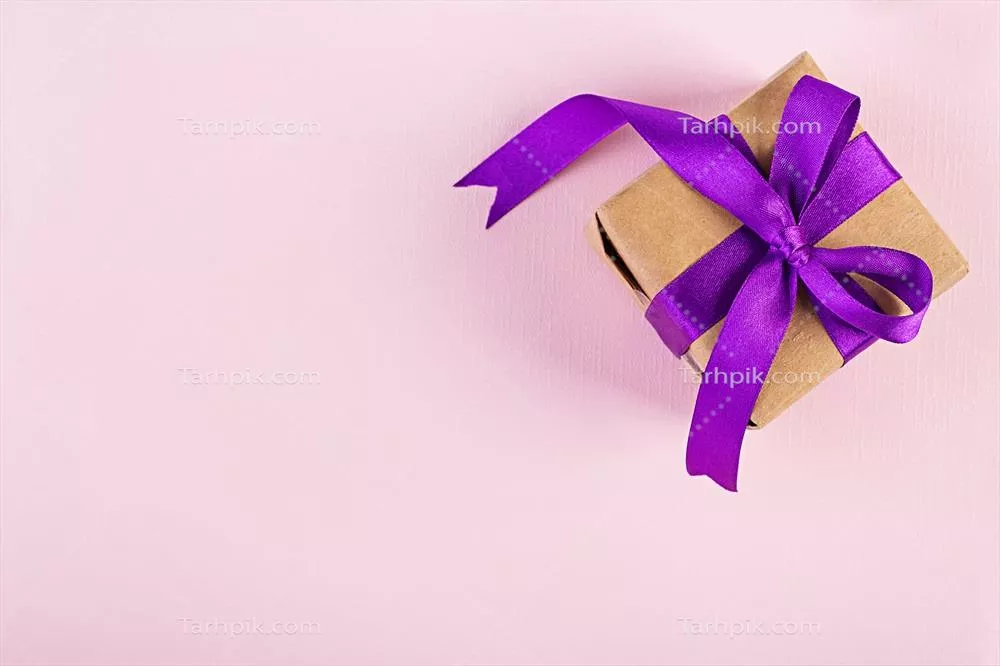 جعبه هدیه با روبان بنفش بر روی پس زمینه صورتی به صورت نمای بالا