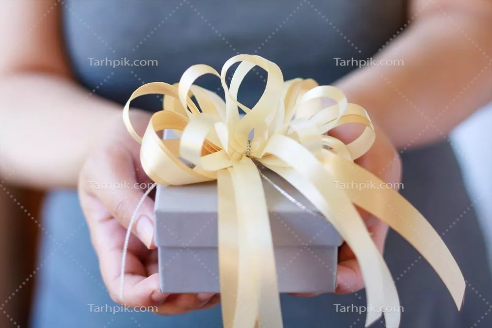 زن با جعبه هدیه در دست و لبخند بر لب، شادی را به تصویر میکشد