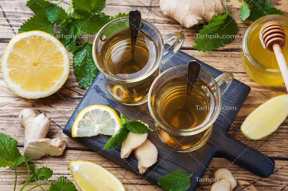 دو فنجان چای گیاهی طبیعی با طعم زنجبیل، لیمو، نعناع و عسل بر روی یک پسزمینه چوبی