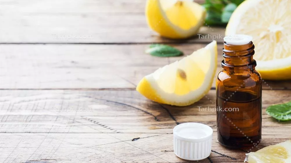 روغن لیمو خالص در بطری با برشهای تازه میوه بر روی پسزمینه چوبی