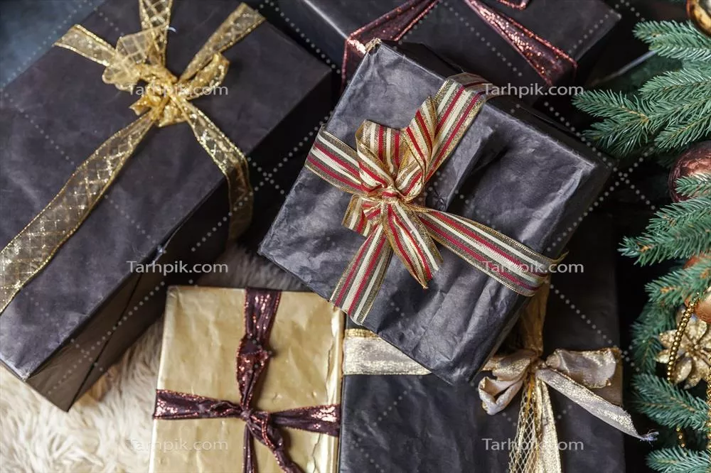 درخت کریسمس کلاسیک تزئین شده برای سال نو با جعبههای هدیه طلایی و مشکی و دکوریهای زیبا