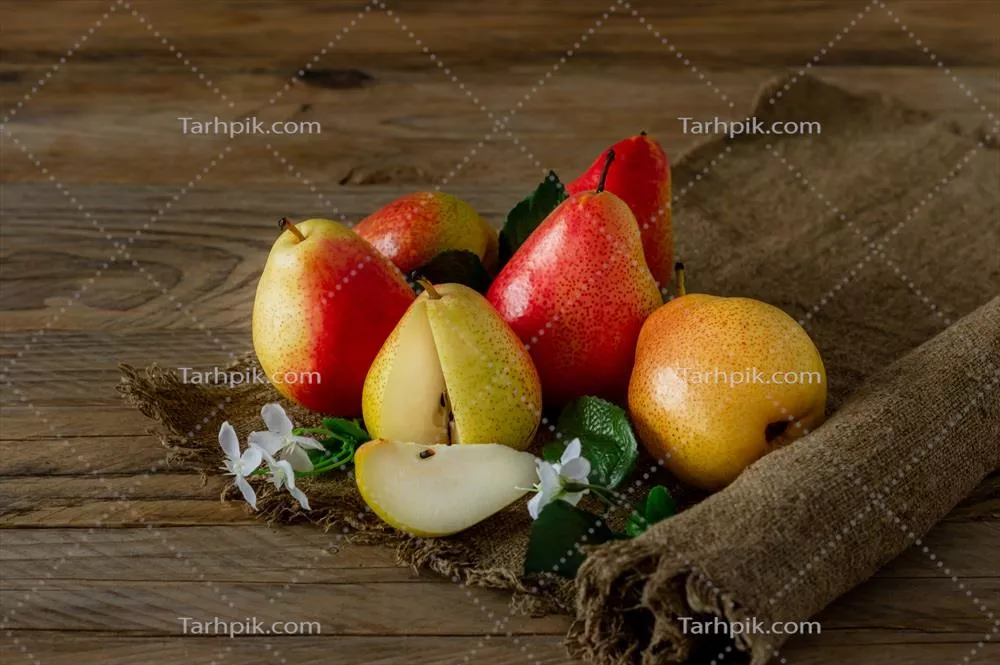گلابی های رسیده برداشت شده ارگانیک که روی پارچه کرباس بر روی میز چوبی در فصل پاییز قرار دارند