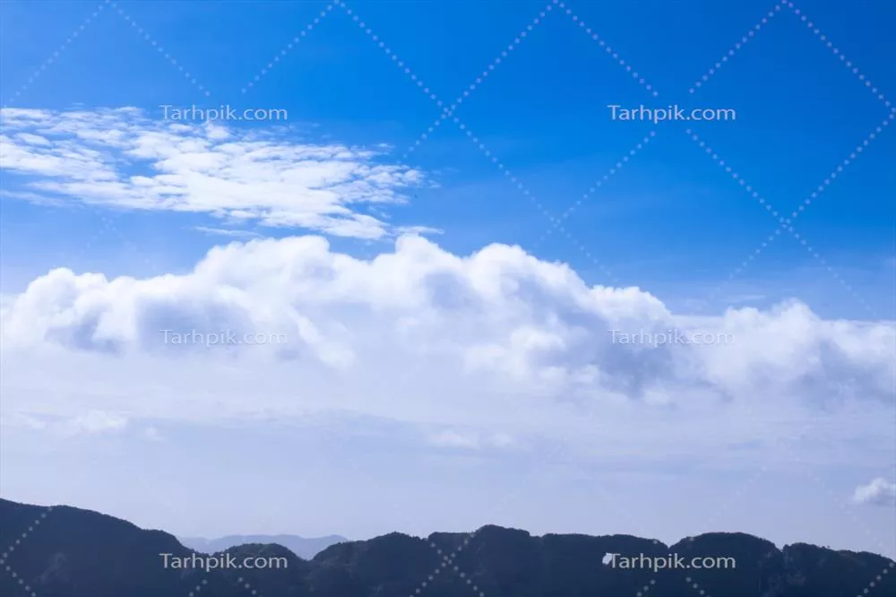 پیشزمینه زیبا شامل درختان سبز و کوهها در آسمان آبی و ابرها