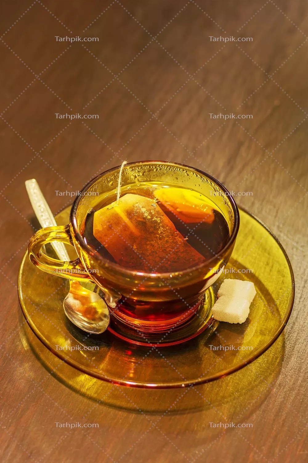 ماگ دمنوش داغ با چای کیسه‌ای، قاشق و شکر روی میز