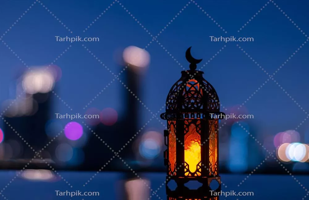 تمرکز انتخابی بر چراغانی با نماد ماه بر فراز آن در پس‌زمینه شهری برای جشن مسلمانان در ماه مبارک رمضان