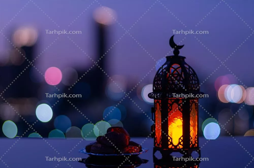 فوکوس انتخابی بر روی چراغی با نماد ماه و بشقابی از خرما برای رمضان مبارک