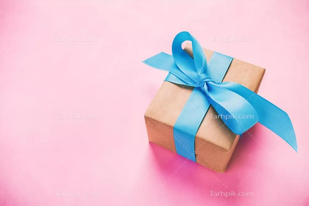 هدیه بسته بندی شده و تزئین شده با روبان آبی بر روی پس زمینه صورتی با تزئینات و فضای خالی
