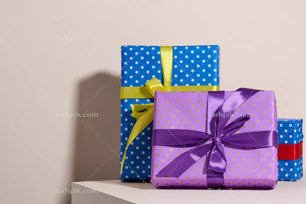 جعبه هدیه زیبا با بسته بندی کاغذی بنفش فانتزی و روبان ابریشمی روی پس زمینه کرم