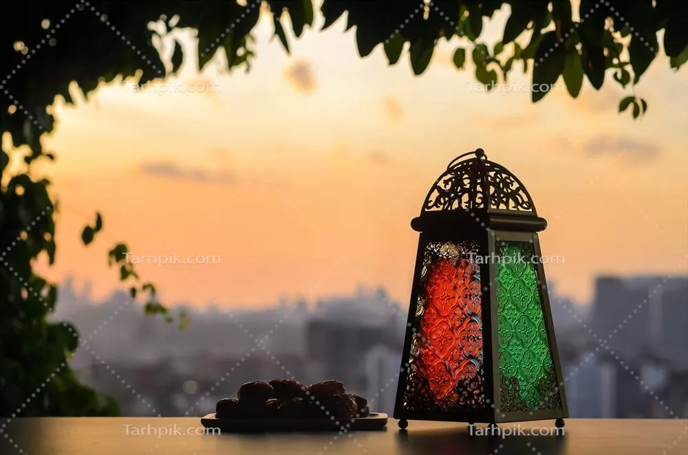 چراغ و خرما در آسمان غروب و پس‌زمینه شهری برای جشن ماه مبارک رمضان کریم