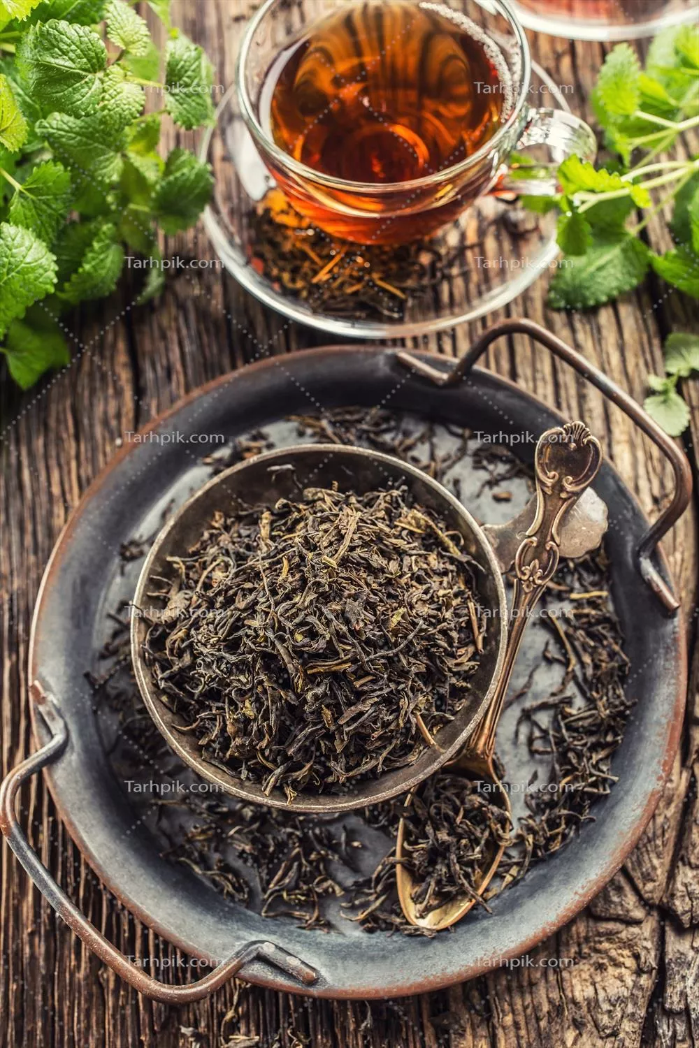 برگهای چای خشک در کاسهای بر روی میز چوبی روستایی