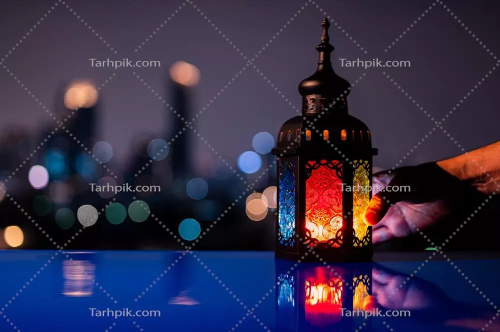 چراغ‌دستی روی میز با پس‌زمینهٔ آسمان شب و بُکِهٔ شهری برای ماه مبارک رمضان کریم