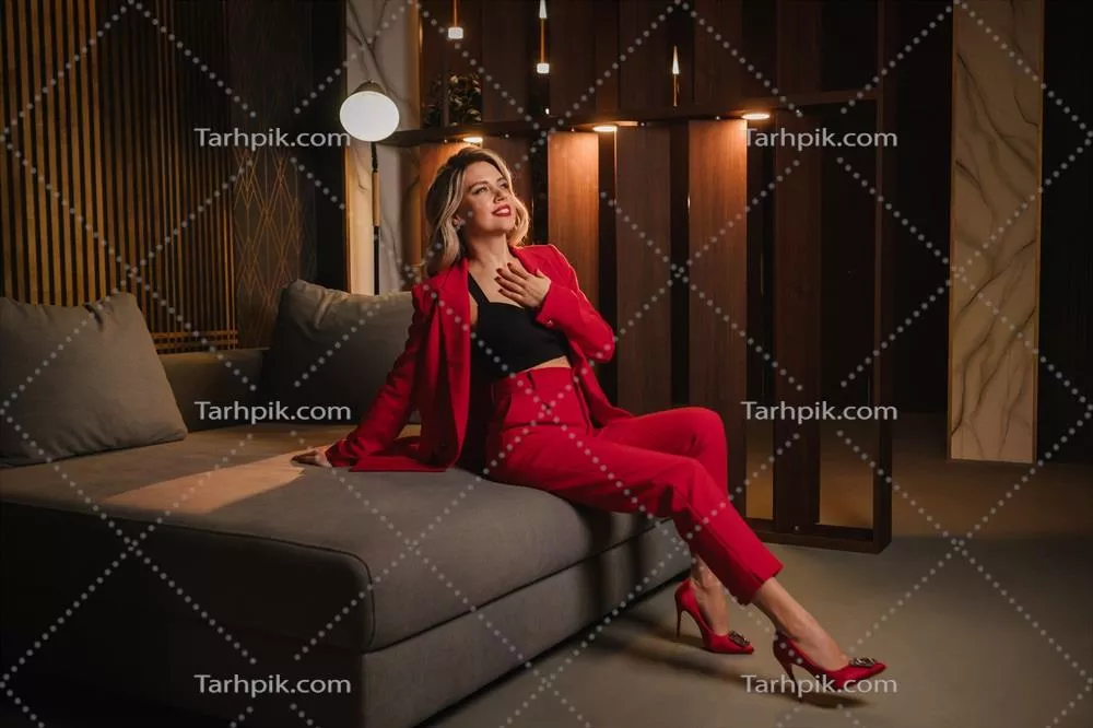 دختر زیبایی که در یک کت و شلوار رسمی قرمز در یک فضای مدرن قرار دارد