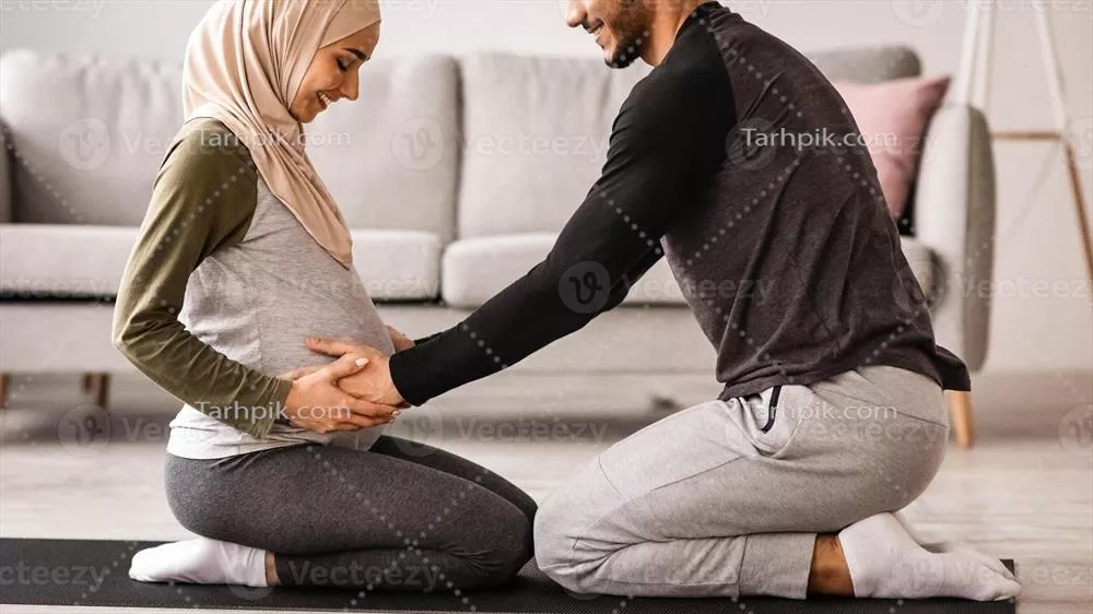 مرد عرب مهربان در حال لمس شکم باردار همسرش در حین تمرین یوگا در خانه