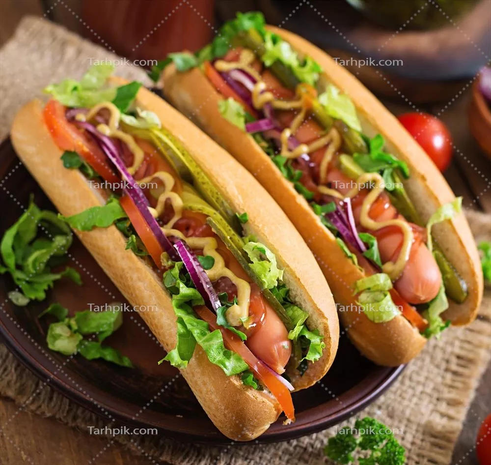 هامبرگر داغ با خیار شور، گوجه فرنگی و کاهو بر روی زمینه چوبی