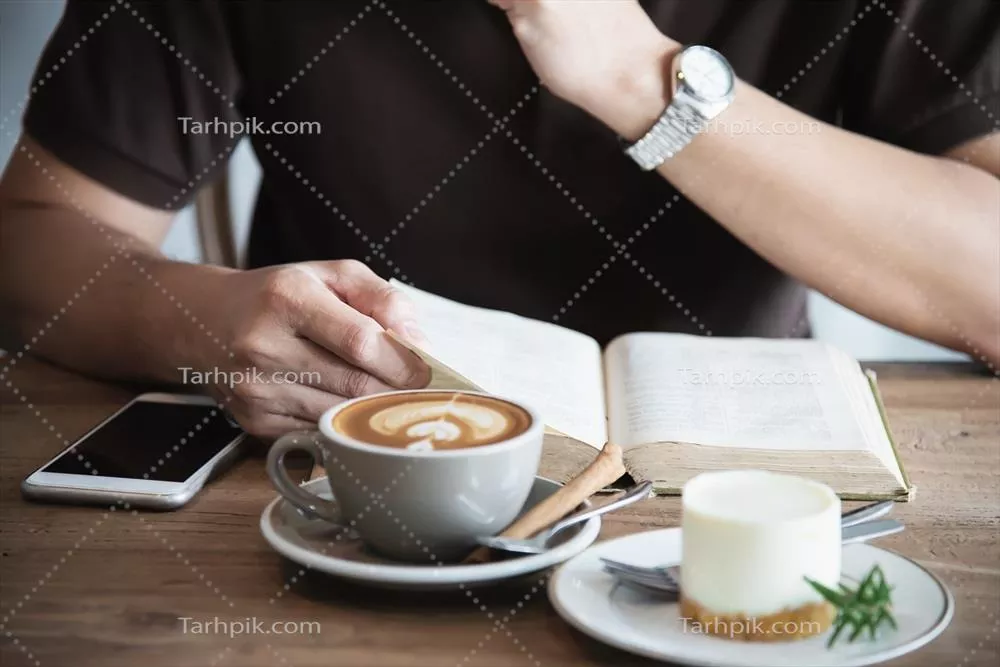 عکس مرد آسیایی آرام در کافه مدرن کتاب میخواند و قهوه مینوشد