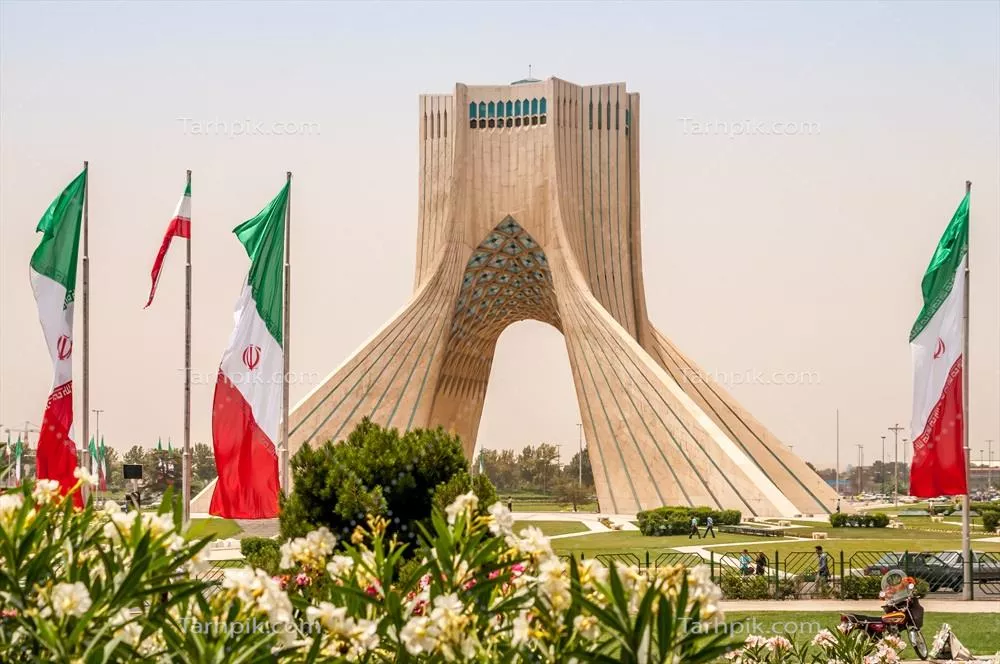 عکس منظرهای از برج آزادی تهران با پرچمهای درحال اهتزاز