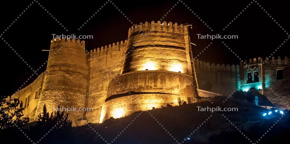 عکس نمای شب قلعه باستانی با دیوارهای سنگی و تامین نور جذاب