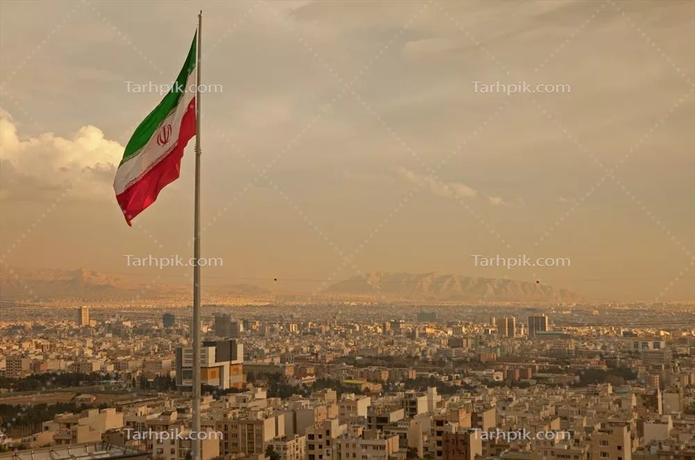 عکس پرچم ایران بر فراز شهر تهران با کوههای البرز در پسزمینه