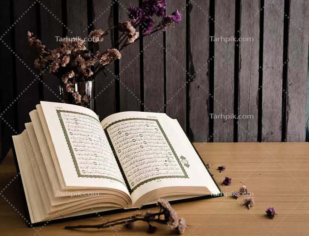 عکس کتابی مقدس باز شده روی میز چوبی با گلهای خشک در پسزمینه