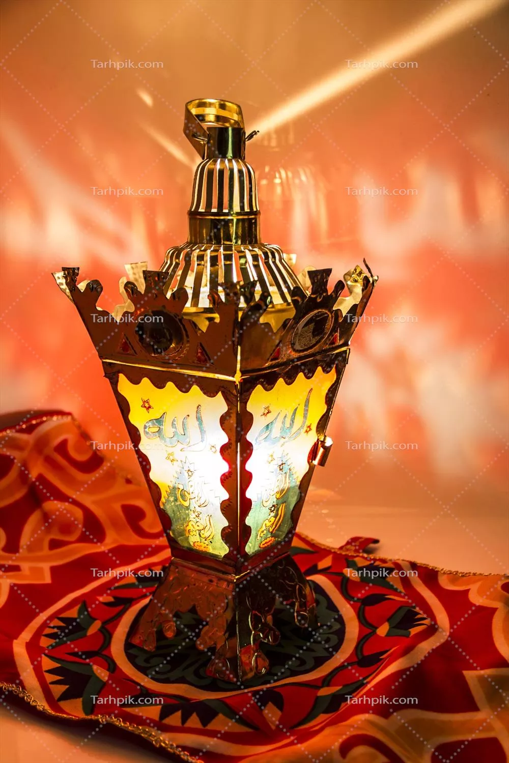 عکس چراغ سنتی با طرح شرقی روی پارچه رنگارنگ با نورپردازی گرم