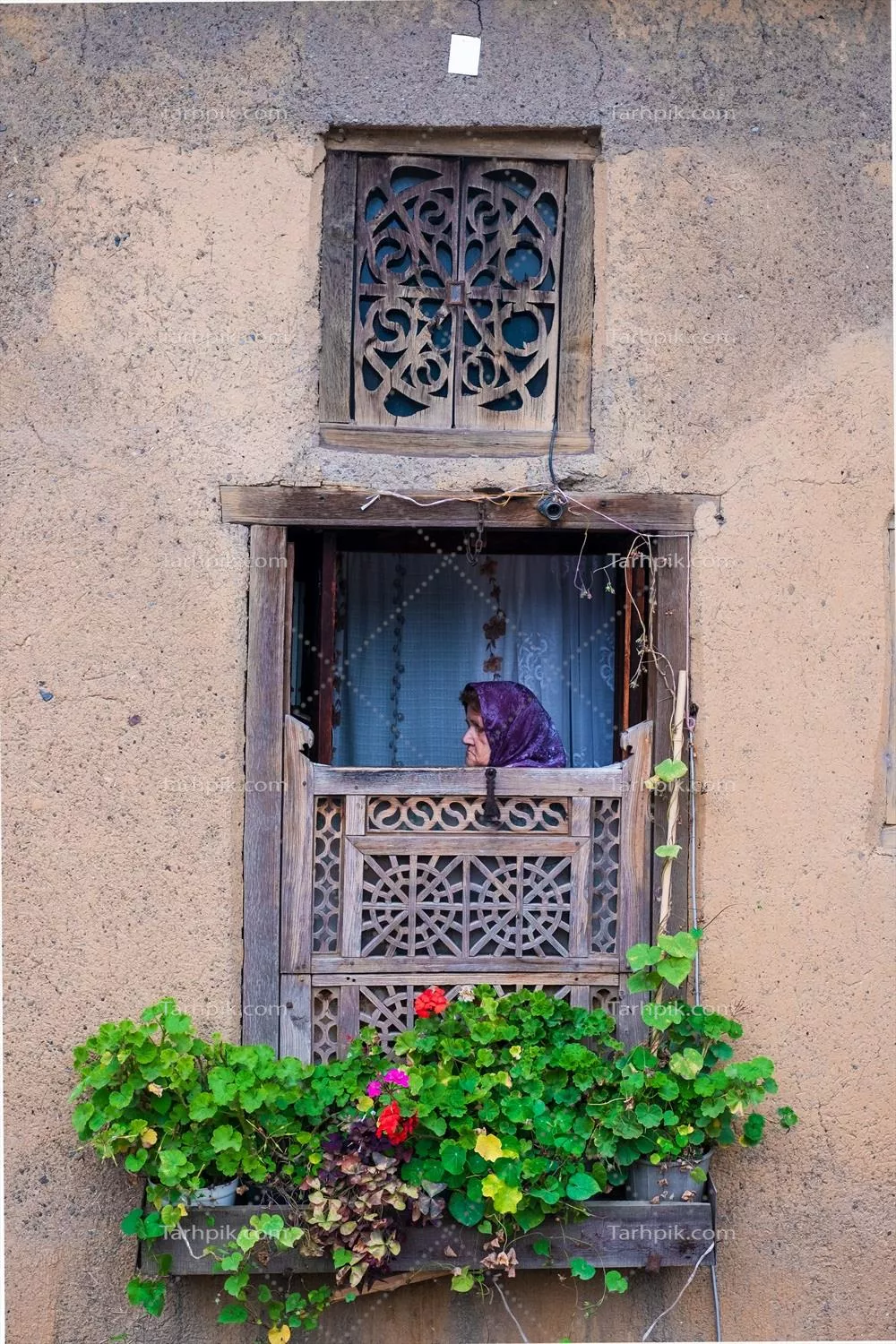 عکس تصویری زیبا از پنجره سنتی با گلدان و زن در پشت آن