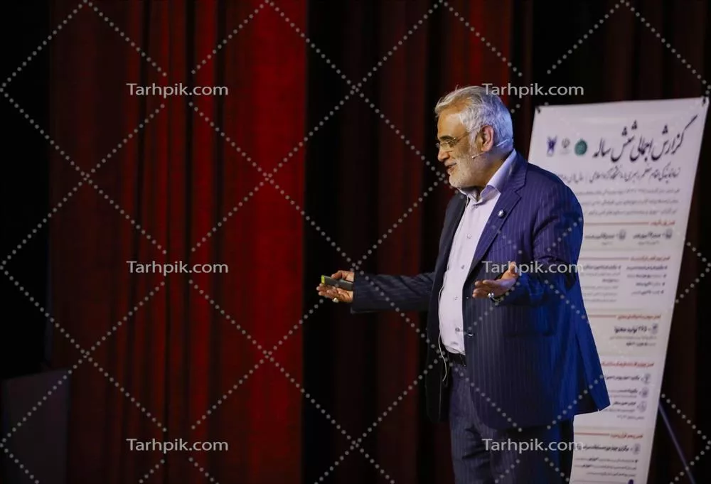 عکس سخنرانی مرد در مقابل پوستر در محیط همایش با پرده های قرمز