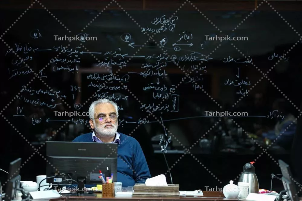 عکس استاد در مقابل تخته شیشهای با نوشتههای علمی در کلاس درس