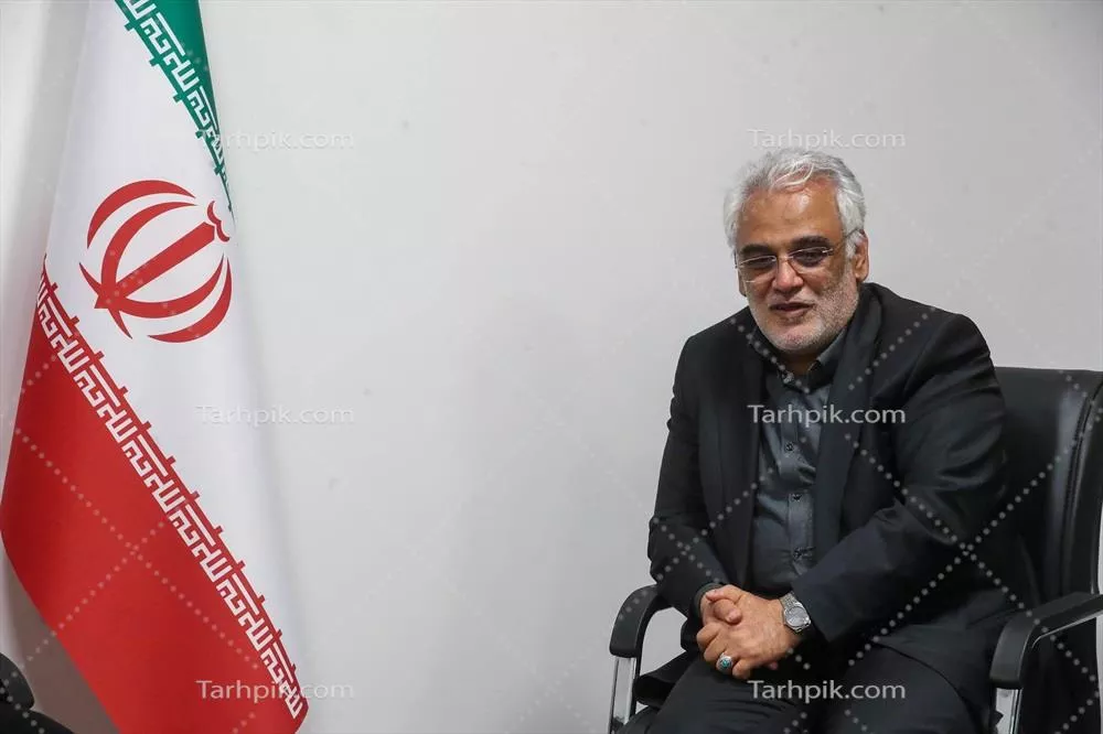 عکس نشست مرد در دفتر با پرچم ایران در پسزمینه
