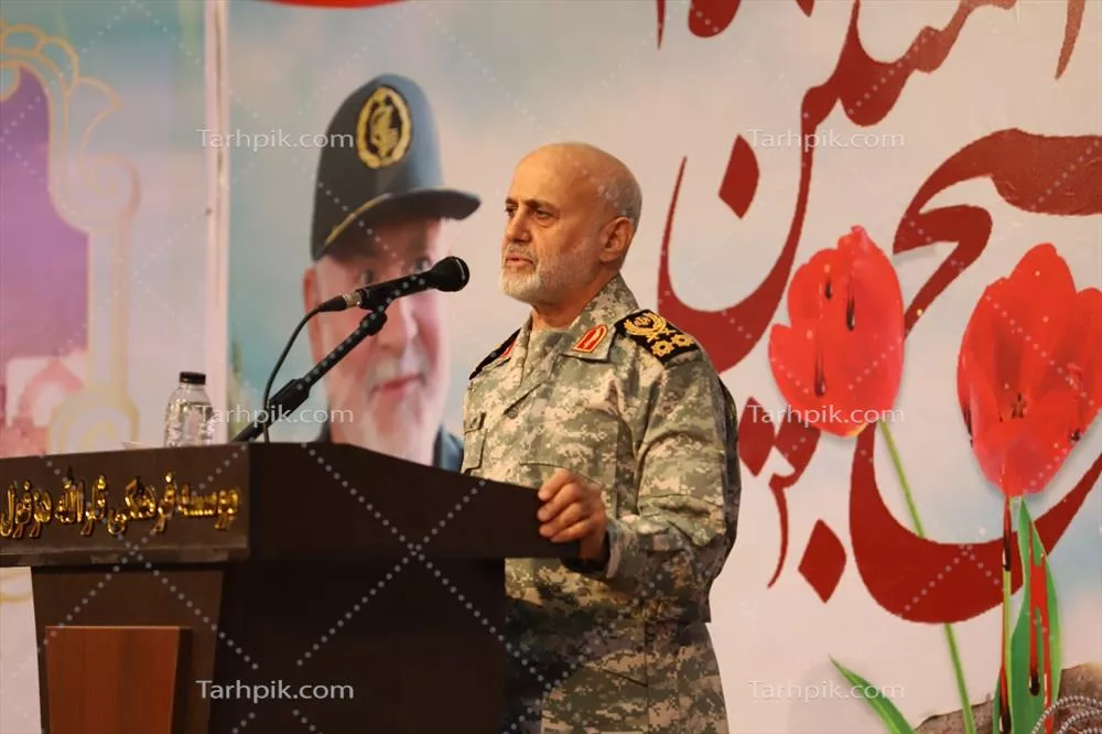 عکس سخنرانی نظامی در مراسم بزرگداشت با پسزمینه گلهای سرخ
