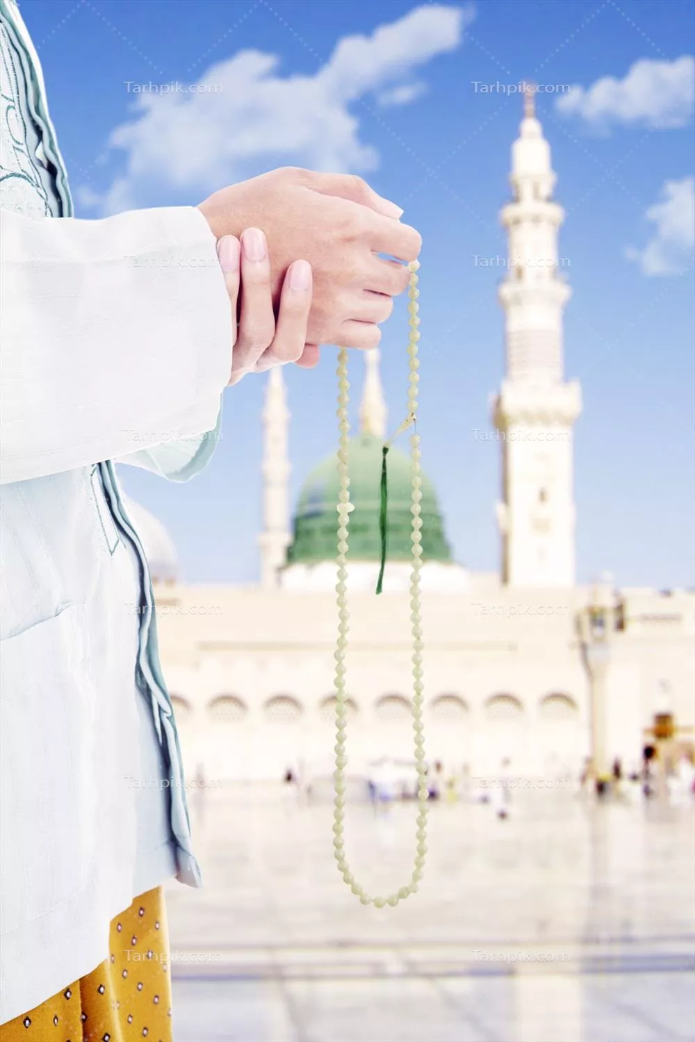 عکس دست مرد مسلمان با تسبیح در مسجد با گنبد سبز و مناره