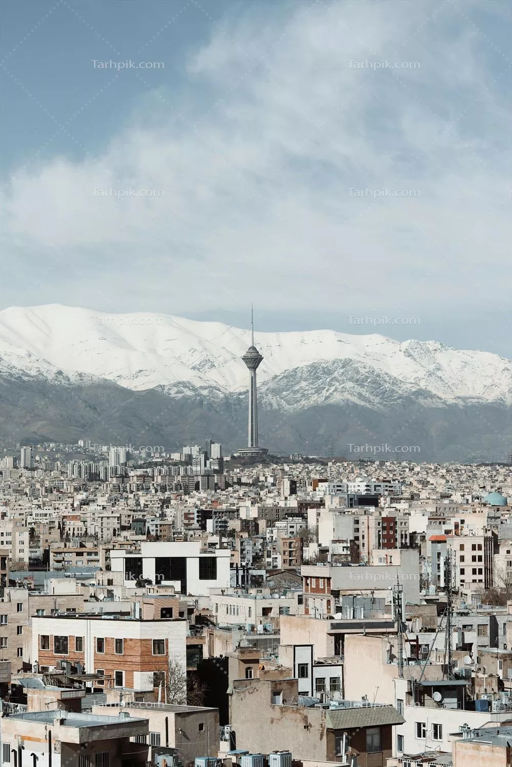 عکس نمایی زیبا از برج میلاد تهران با پسزمینهی کوههای پوشیده از برف