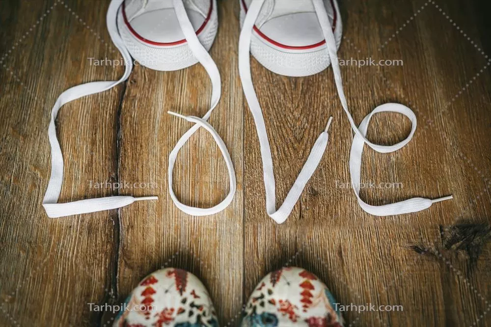 عکس طراحی و نگارش عشق با بندهای کفش بر روی زمین چوبی برای روز ولنتاین