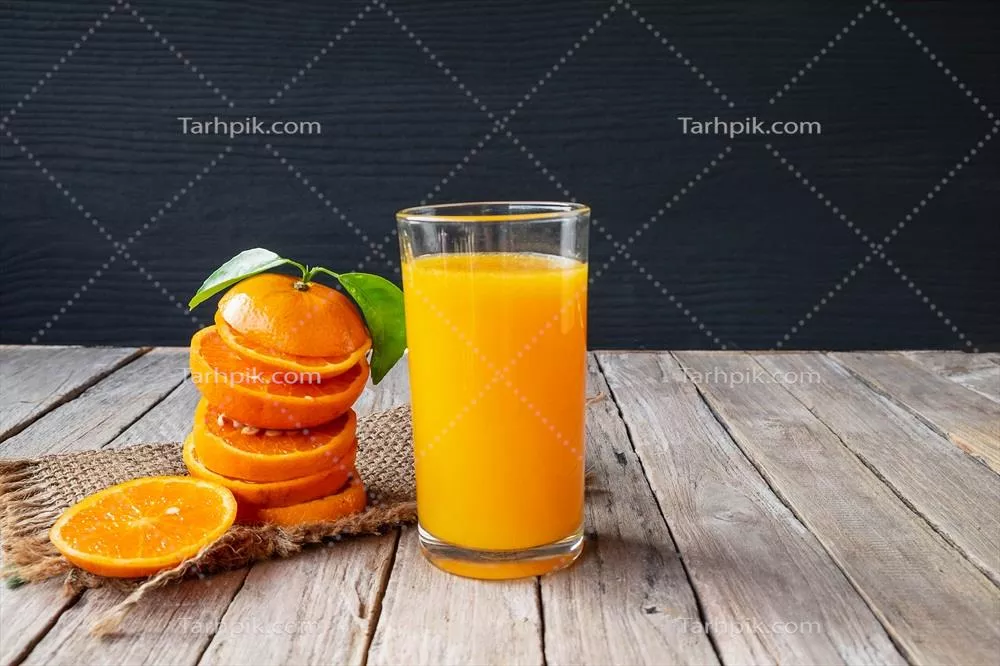 عکس پرتقال تازه و آب پرتقال در کنار هم بر روی میز چوبی