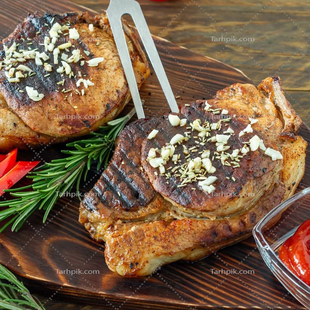 عکس گوشت قرمز کبابی تازه و آبدار بر روی تخته چوبی با ادویه‌جات و سبزیجات