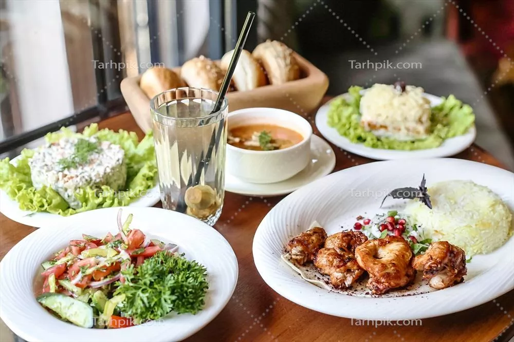 عکس میز چوبی زیبا با بشقاب‌های خوشمزه و انواع غذاهای لذیذ