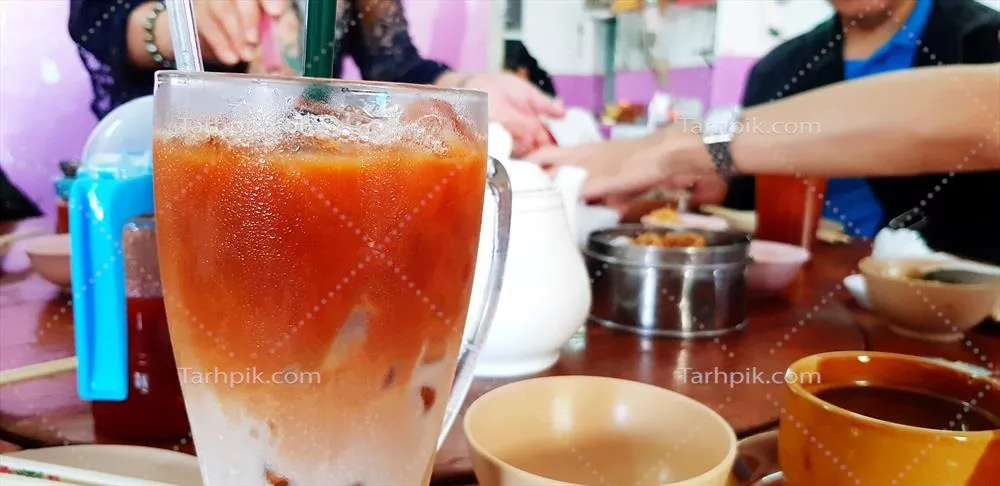 عکس نوشیدنی شیر چای سرد در رستوران چینی با غذاهای متنوع در پس‌زمینه