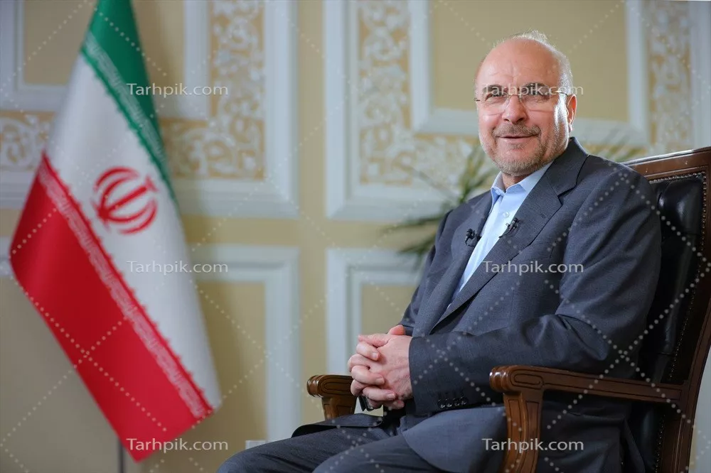عکس دکتر قالیباف نشسته روی صندلی وپرچم ایران در پس زمینه