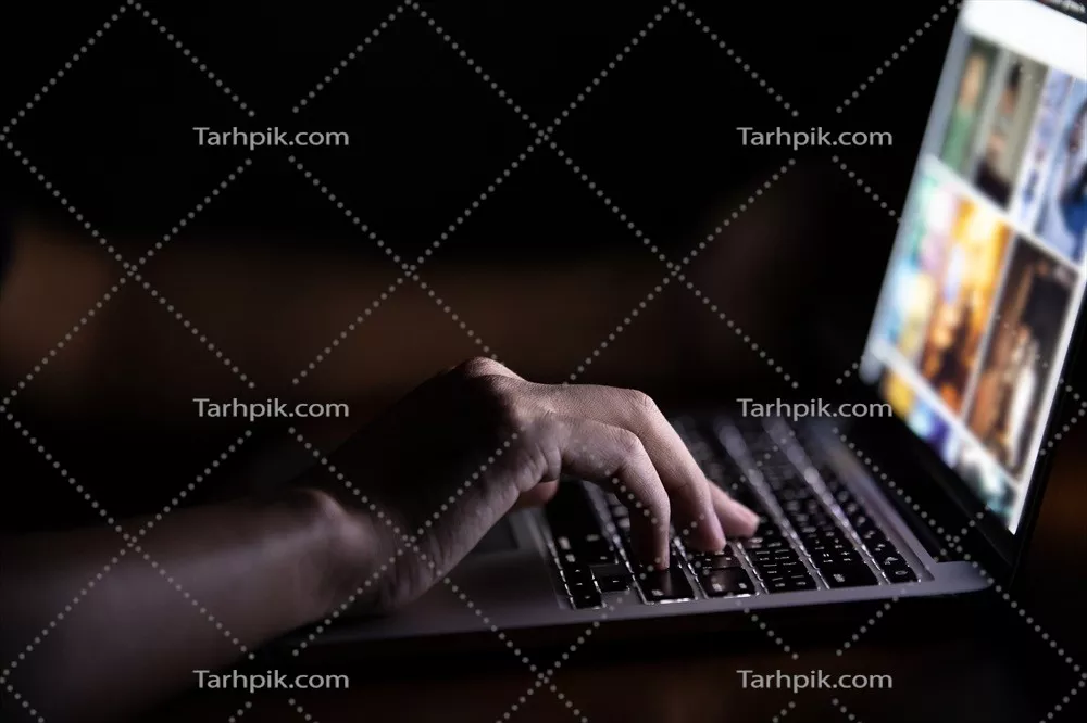 عکس مردی که در شب به کمک کامپیوتر قابل حمل مشغول به کار است